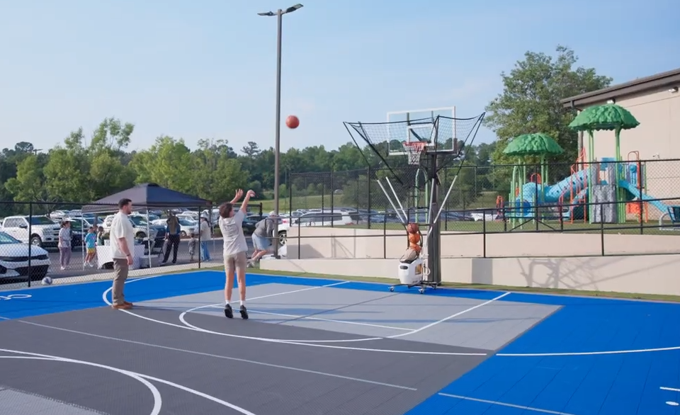 kids playing basketball on a versacourt basketball court with a dr dish shooting machine