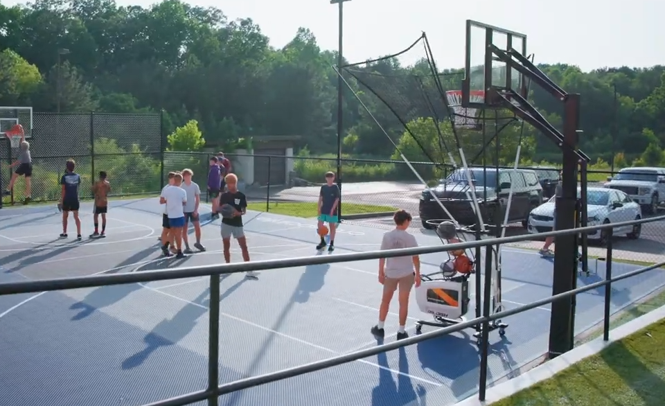 kids playing basketball on a versacourt basketball court with a dr dish shooting machine