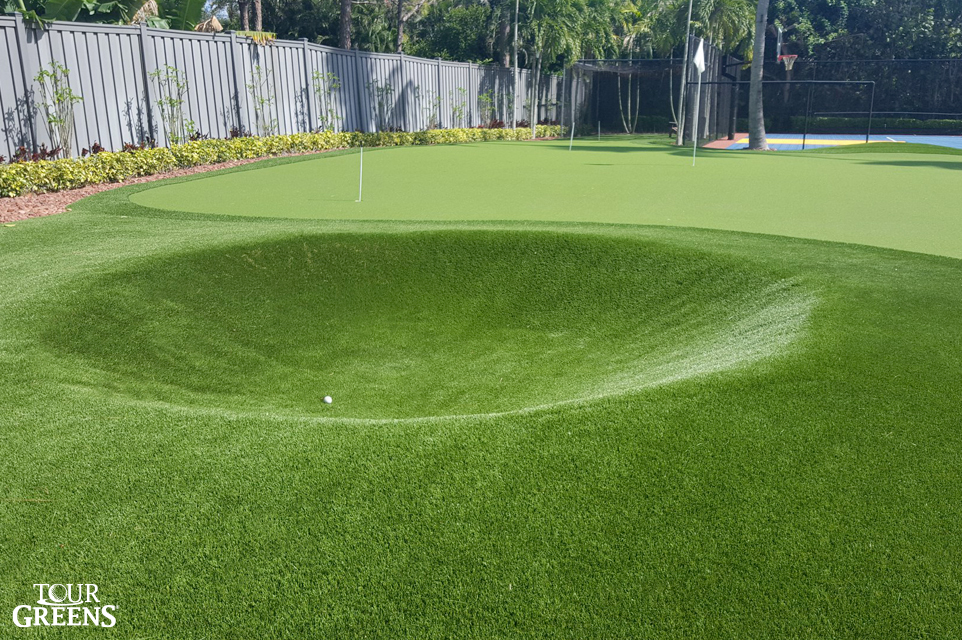 Large backyard with tour quality putting green with a sand trap and bunker