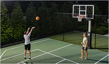 two men playing basketball in front of a Dominator basketball goal