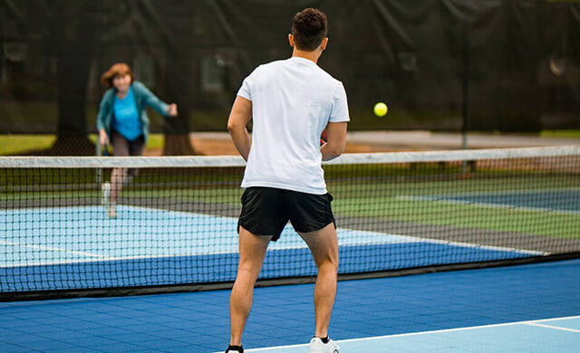 a couple playing pickleball on blue and light blue court