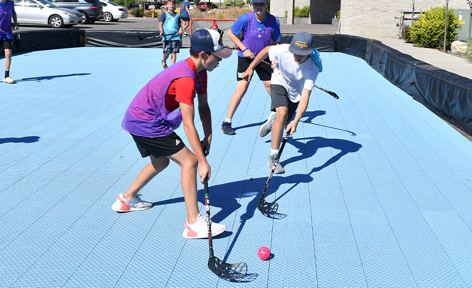kids gather around on a bright blue VersaCourt game court listening to a coach