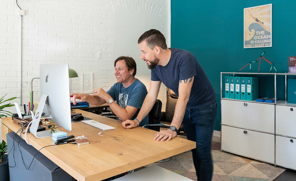 Two men collaborating in front of computer screen